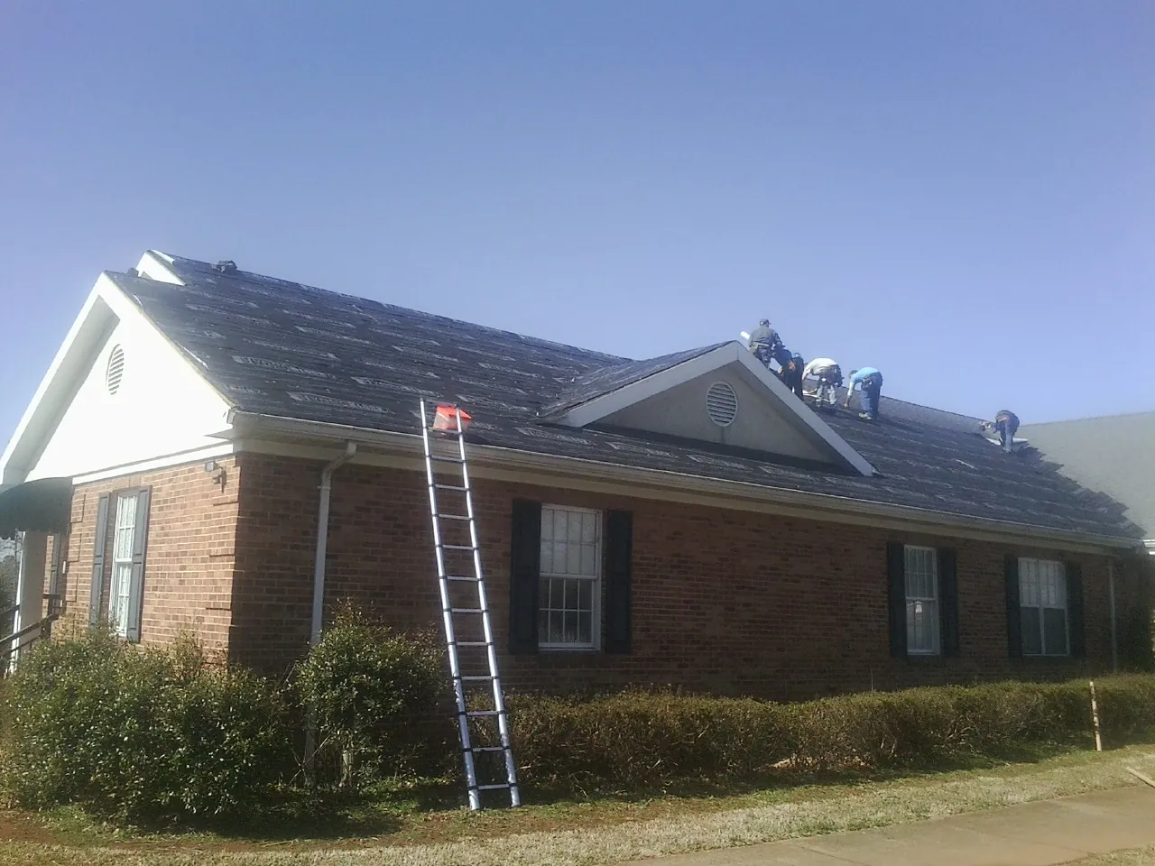 Crew tearing shingles off a brick ranch roof with a ladder set — Metal Roof Repair work by our crew in Cerritos