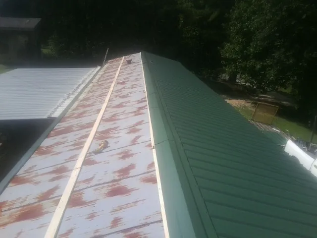 Old rusted panels beside newly installed green metal roofing — Wind Damage Roof Repair by Roofing Brothers in Cerritos