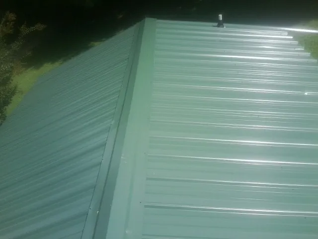 New green metal panels meeting at the ridge of a roof — Flat Roof Repair work by our crew in Cerritos