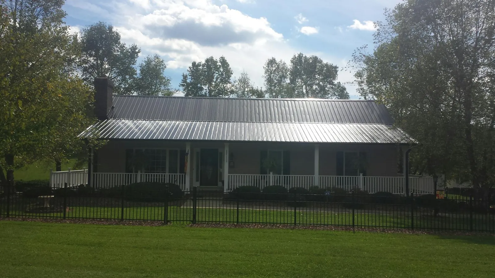 Gray metal roof on a brick ranch with a full width front porch — Gutter Guard Installation work by our crew in Cerritos