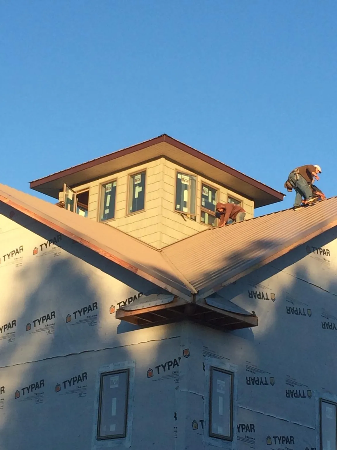 Roofers working around a rooftop cupola on a new metal roof at sunset — Roof Waterproofing in Cerritos by Roofing Brothers